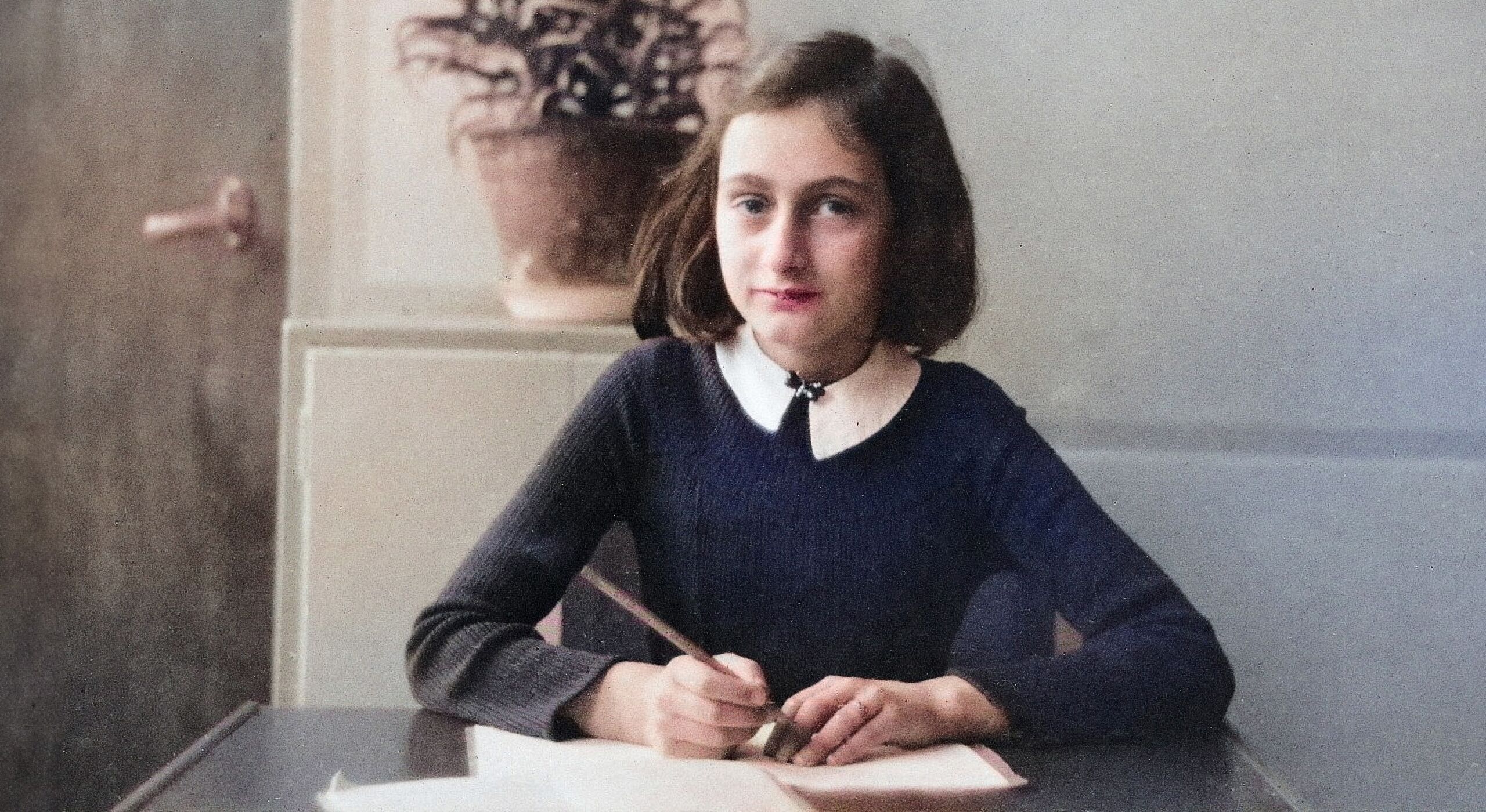 Anne Frank schreibt vor dem Tisch